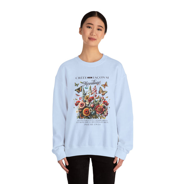 Une femme porte un sweat-shirt bleu clair orné d'un motif floral et de papillons avec un texte.
