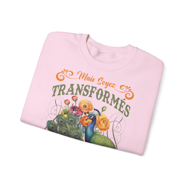 Sweat-shirt rose pâle plié avec une illustration de paon, de fleurs et le texte Mais Soyez Transformés.
