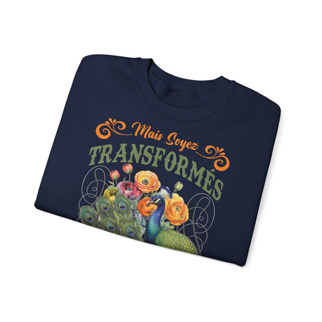 Sweat-shirt bleu marine plié avec une illustration de paon, de fleurs et le texte Mais Soyez Transformés.