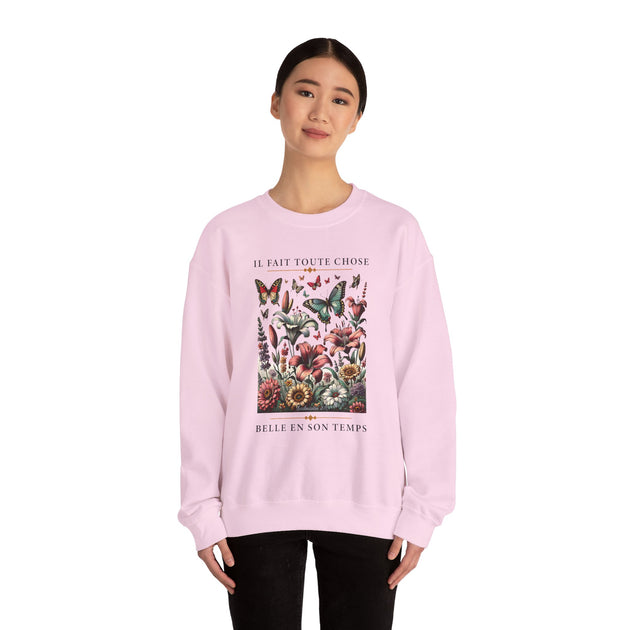 Une femme porte un sweatshirt rose pâle orné d'un motif floral et de papillons avec du texte.