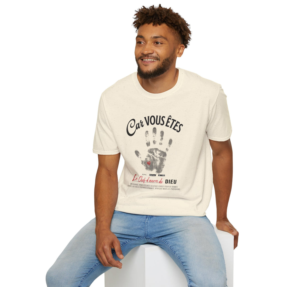 Un homme porte un t-shirt beige chiné avec une empreinte de main et un texte religieux.