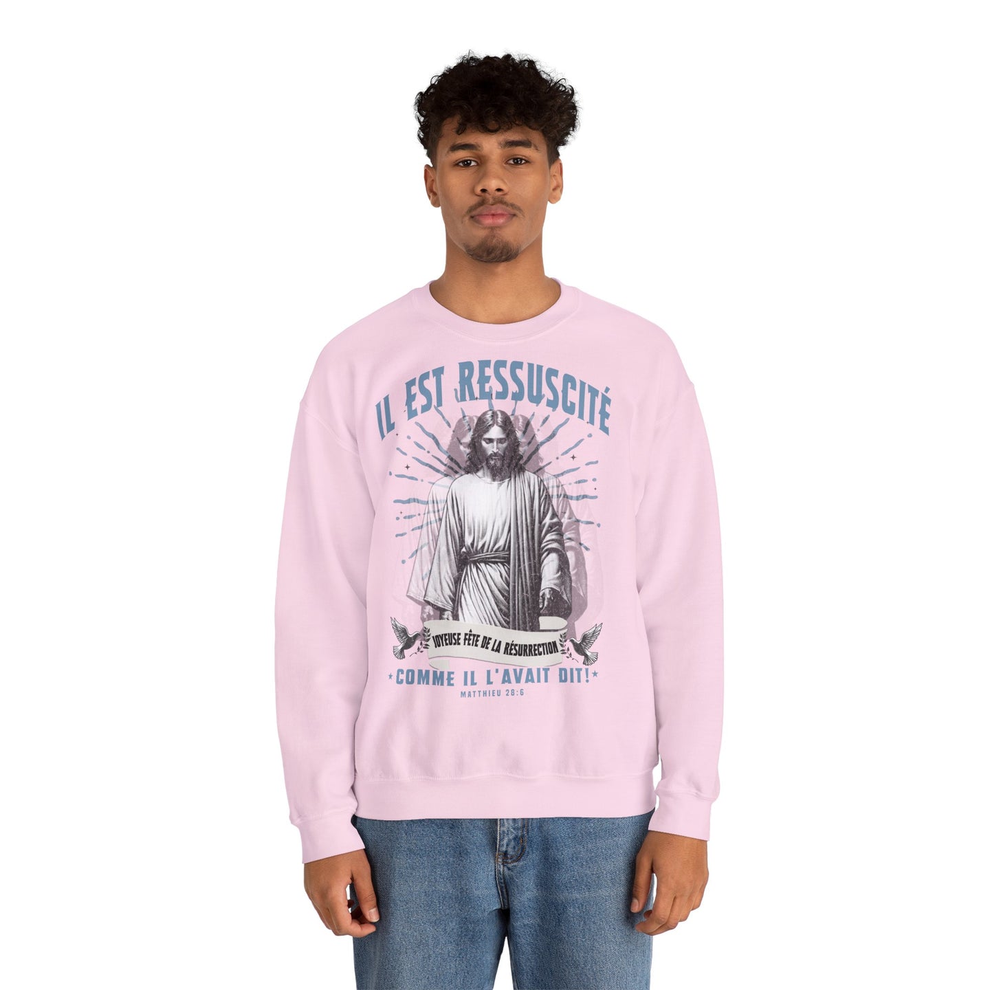Un homme porte un sweatshirt rose pâle avec une illustration religieuse et le texte Il est ressuscité.