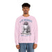 Un homme porte un sweatshirt rose pâle avec une illustration religieuse et le texte Il est ressuscité.
