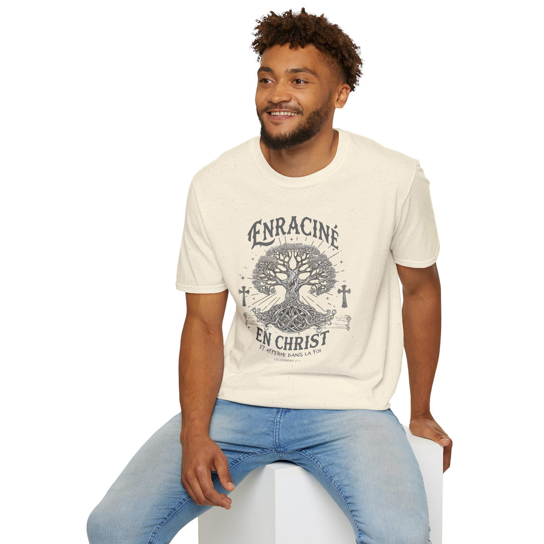 Un homme porte un t-shirt beige chiné avec une illustration d'arbre et le texte Enraciné en Christ.