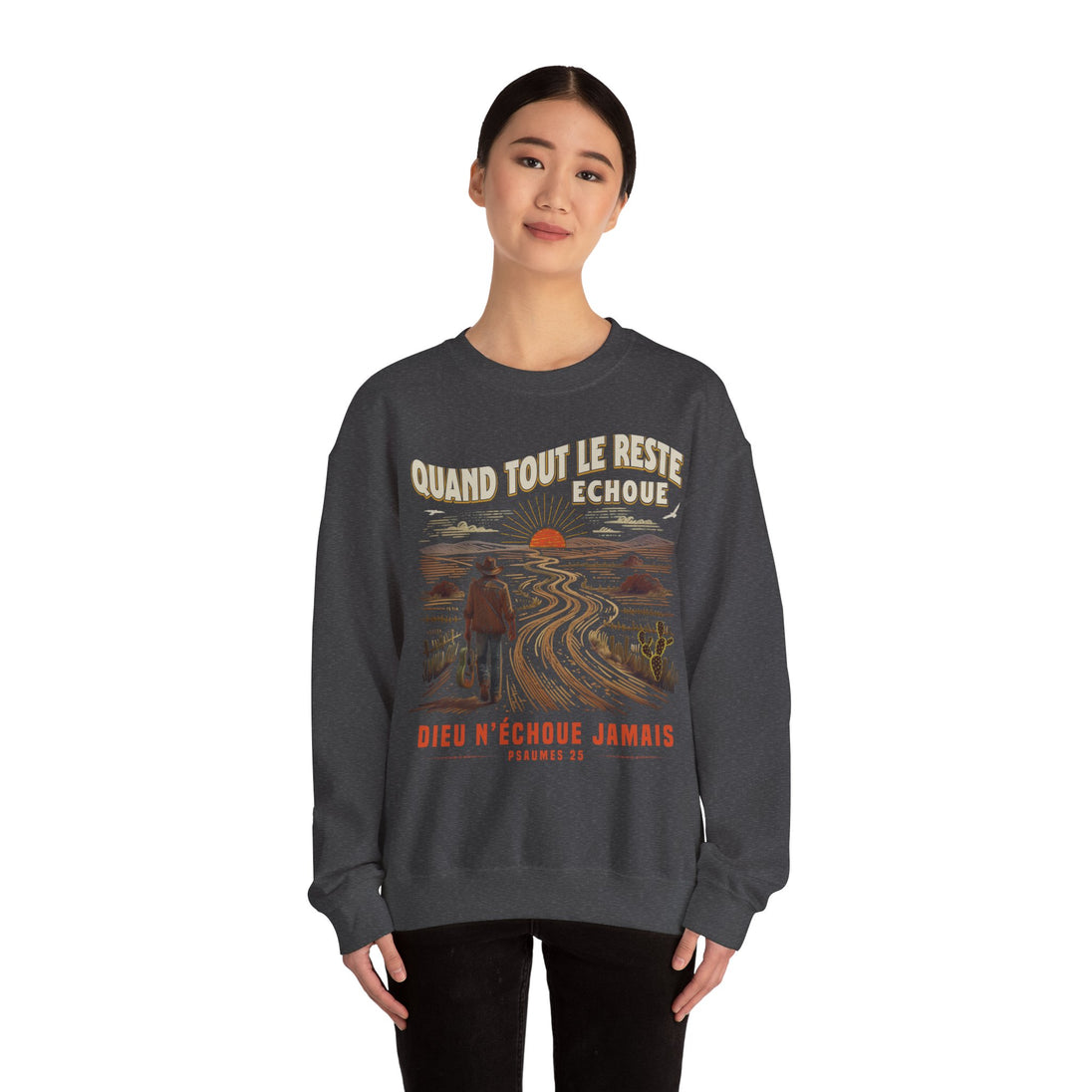 Une femme porte un sweat-shirt gris foncé avec une illustration de paysage et un message religieux.