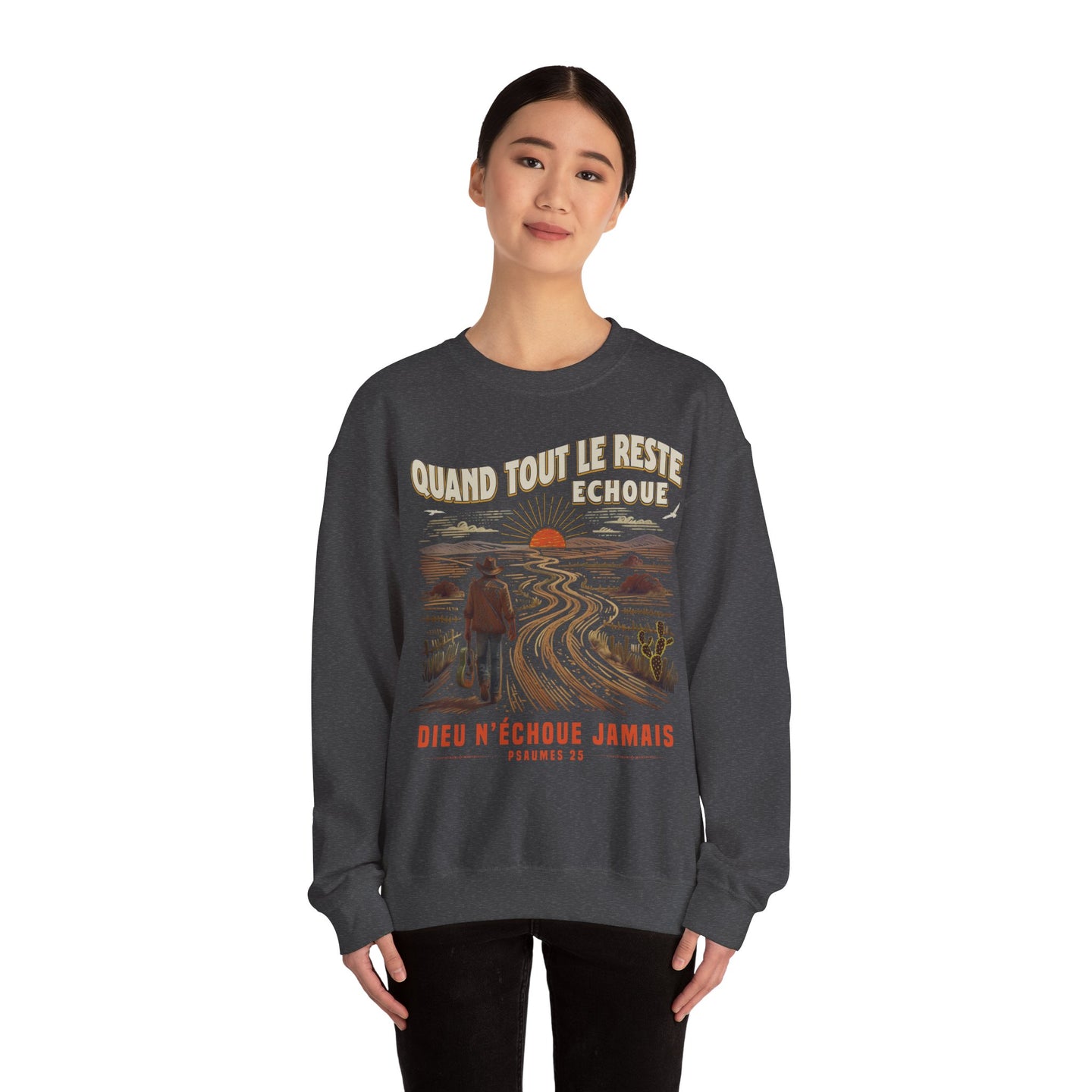 Une femme porte un sweat-shirt gris foncé avec une illustration de paysage et un message religieux.