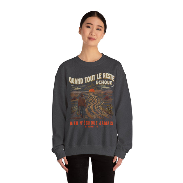 Une femme porte un sweat-shirt gris foncé avec une illustration de paysage et un message religieux.
