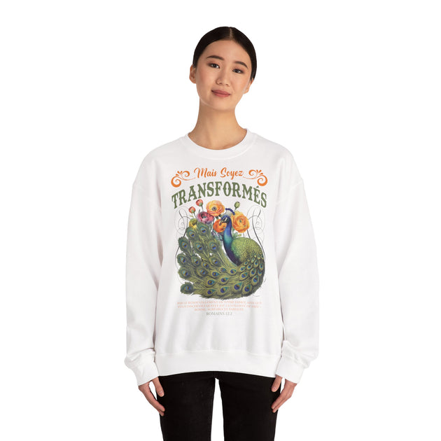 Une femme porte un sweat-shirt blanc orné d'un paon, de fleurs et du texte biblique Romains 12:2.