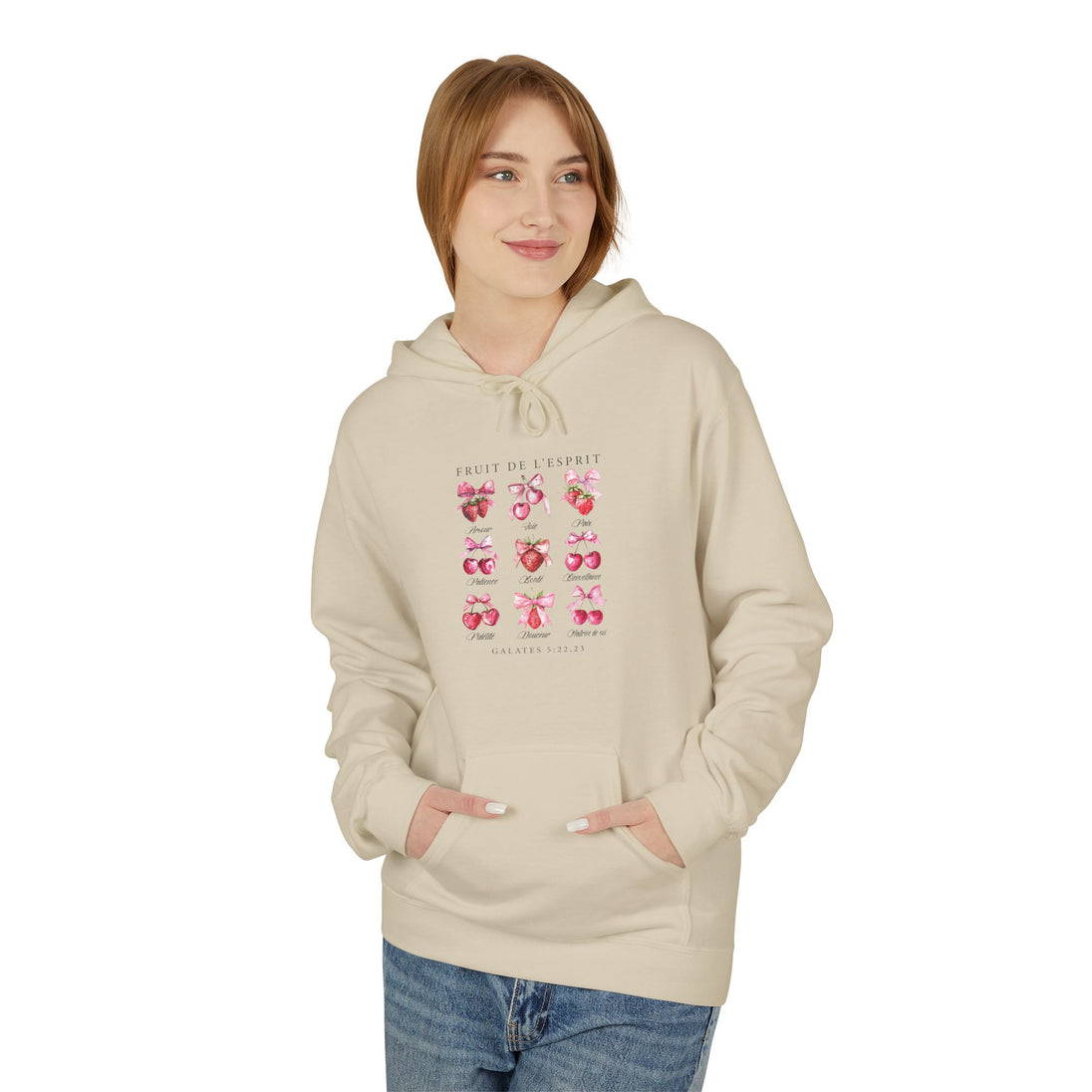 Une femme porte un sweat à capuche beige orné d'un motif de fruits et de nœuds roses.